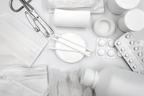 Zoom sur des fournitures médicales et de protection: gants, masque, seringues simulées, comprimés et emballages médicaux.